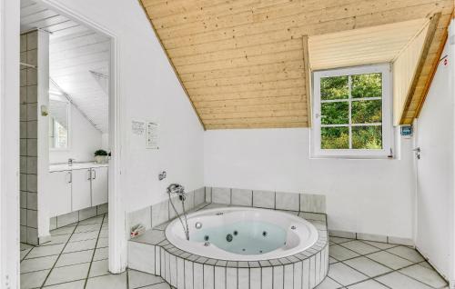 a bathroom with a large tub in a room with a window at Nice Home In Ringkbing With 5 Bedrooms, Private Swimming Pool And Outdoor Swimming Pool in Søndervig