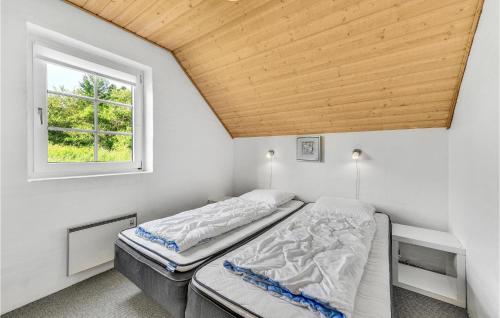 two beds in a room with a window at Nice Home In Ringkbing With 5 Bedrooms, Private Swimming Pool And Outdoor Swimming Pool in Søndervig