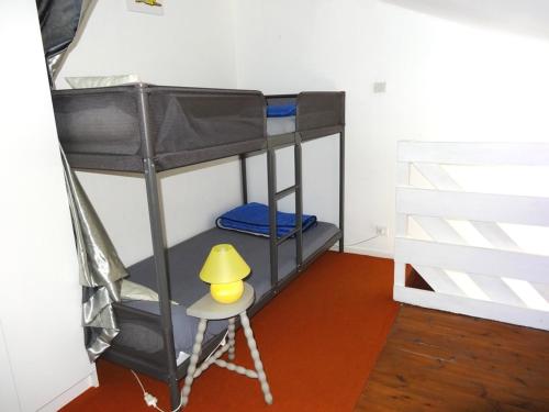 un lit superposé avec une lampe jaune sur un tabouret dans l'établissement Charmante maisonnette proche plage et centre-ville, équipée pour 4 pers., parking, WiFi, La Faute-sur-Mer - FR-1-476-105, à La Faute-sur-Mer