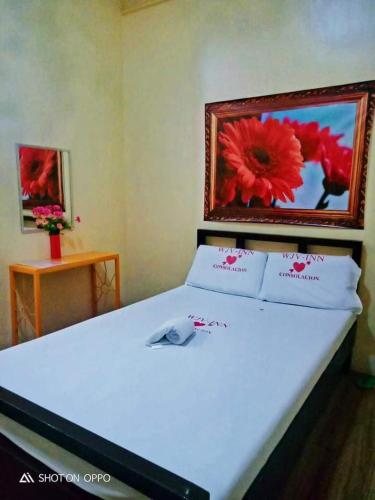 a bedroom with a white bed with a picture on the wall at WJV INN CONSOLACION in Consolation