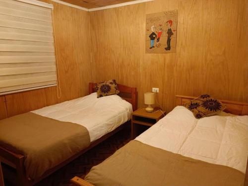 two beds in a room with wooden walls at Centro Turístico El Rey Condorito in Rio Claro