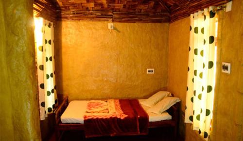 a small room with a small bed with curtains at Greenways Tree House and Mud House in Chekadi