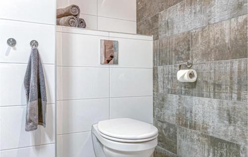 a bathroom with a toilet and a tiled wall at 2 Bedroom Lovely Home In Bruinisse in Bruinisse