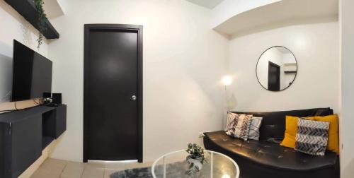 a living room with a leather couch and a mirror at Your Crib - kasara -19 D tower 1 in Manila