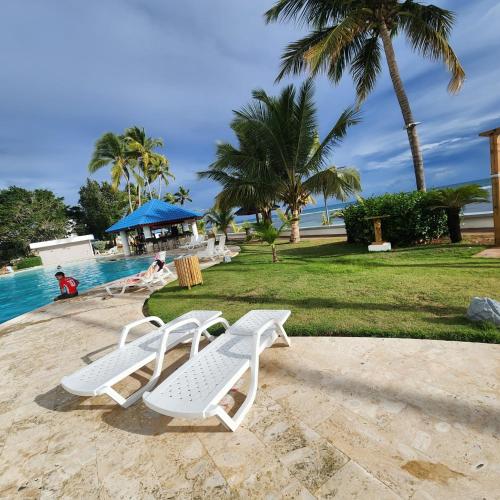 two white lounge chairs next to a swimming pool at Beachfront, Juandolio in Juan Dolio