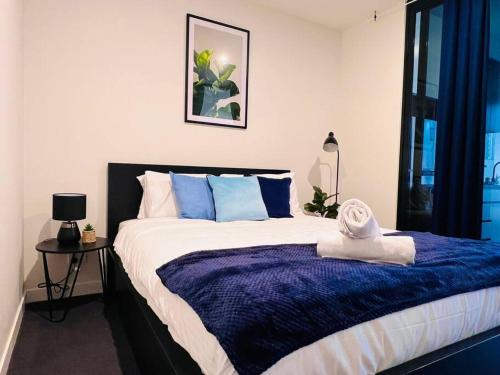 a bedroom with a large bed with blue and white pillows at Comfort City Living 2 Bedroom In Heart of CBD in Melbourne