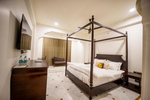 a bedroom with a canopy bed and a desk at ASHOK VILLA in Jaipur