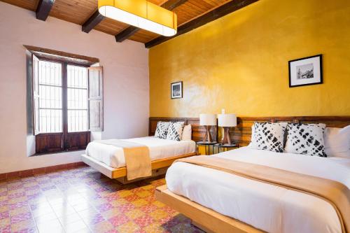 a bedroom with two beds and a yellow wall at Casa I. Madero in Tapalpa