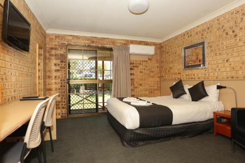 a bedroom with a bed and a table and a desk at Clermont Country Motor Inn in Clermont