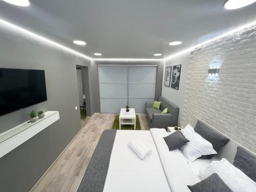 - une chambre avec un lit blanc et un mur en briques dans l'établissement Уютная квартира в центре, à Pavlodar