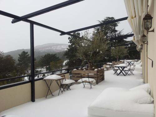 a balcony with snow on the floor and tables and chairs at Hotel Hita "Nature Experience" for all in Navacerrada