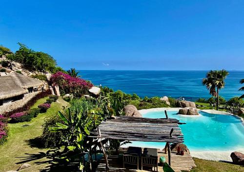 a resort swimming pool with the ocean in the background at Château de feuilles & SPA - Praslin island in Baie Sainte Anne