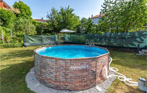 a brick pool in a yard with a hose around it at 2 Bedroom Gorgeous Apartment In Viskovo in Viskovo
