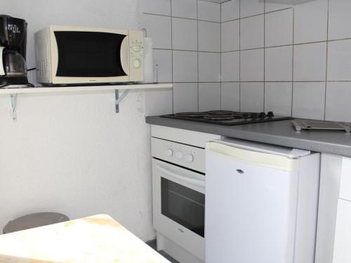 une cuisine avec un micro-ondes et une cuisinière dans l'établissement Apt famille 6 pers avec terrasse, parking et lave-linge à Gruissan - FR-1-229-630, à Gruissan