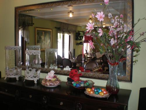 a dresser with a vase of flowers and a mirror at Olympia Guesthouse in Vergina