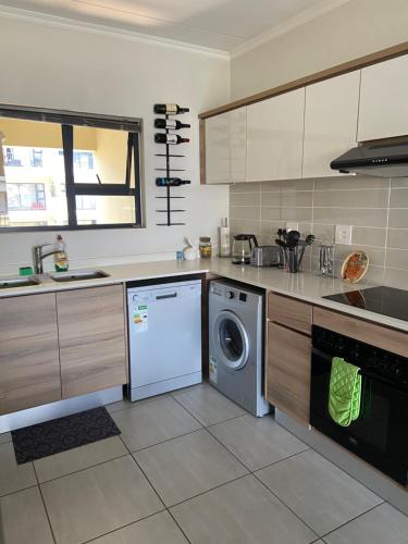 a kitchen with a washing machine and a dishwasher at Loadshedding Equipped 2-Bed Apartment in Waterfall, Waterfall City in Midrand