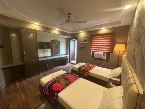 a hotel room with two beds and a couch at Hotel Majestic in Kolkata