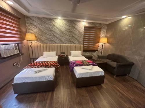 a room with two beds and a chair and a couch at Hotel Majestic in Kolkata