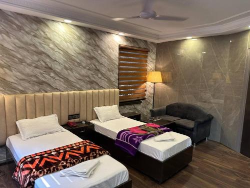 a hotel room with two beds and a chair at Hotel Majestic in Kolkata