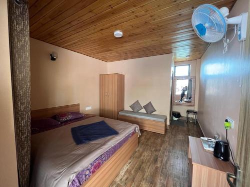 a bedroom with a large bed and a fan at Hidden Cottage in Namchi