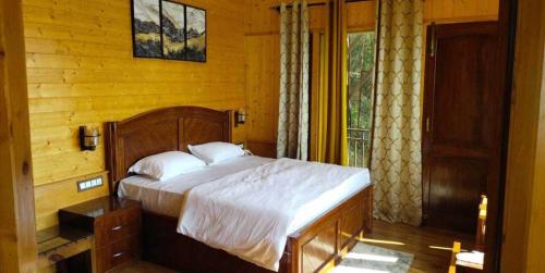 a bedroom with a bed in a wooden room at Atulyam, Pangot in Nainital