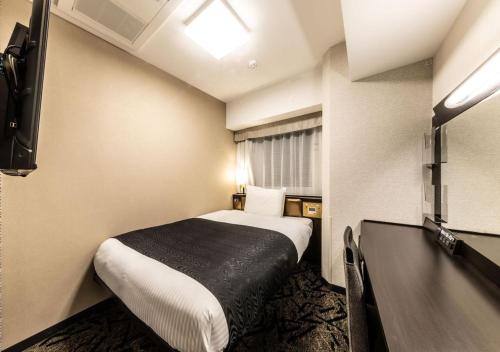 a small hotel room with a bed and a television at APA Hotel & Resort Osaka Umeda Eki Tower in Osaka