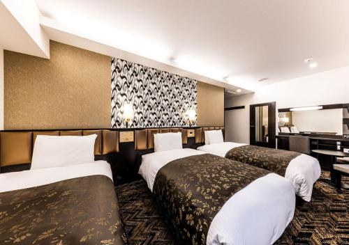 a hotel room with three beds and a desk at APA Hotel & Resort Osaka Umeda Eki Tower in Osaka