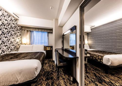a hotel room with two beds and a desk at APA Hotel & Resort Osaka Umeda Eki Tower in Osaka