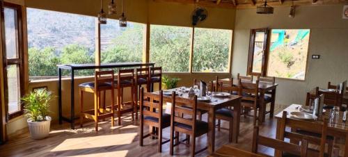 a restaurant with wooden tables and chairs and windows at Atulyam, Pangot in Nainital
