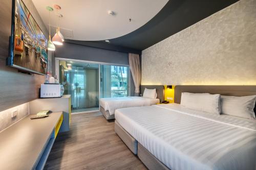 a hotel room with two beds and a tv at Qiu Hotel Sukhumvit SHA Plus in Bangkok