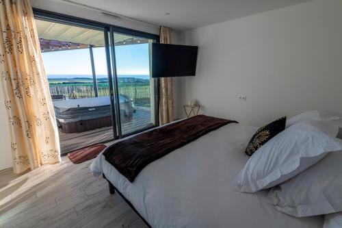 - une chambre avec un grand lit et une grande fenêtre dans l'établissement Vue à Couper le Souffle - Villa de Charme avec Spa en Bord de Mer - Pointe Finistère, à Plougonvelin