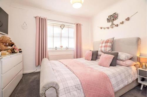 a bedroom with a bed with pink and gray pillows at Comfortable three Bedroom House in great Durham City in Durham