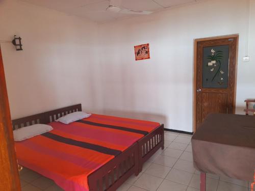 um quarto com uma cama, uma mesa e uma porta em Bandula's Beach Inn em Hikkaduwa