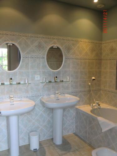 a bathroom with two sinks and a tub and mirrors at Château de Fourcès in Fourcès