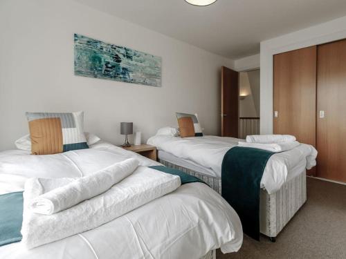 una camera d'albergo con due letti con asciugamani sopra di Cotswolds Lakehouse, with hot tub & spa access, Lower Mill Estate a Somerford Keynes