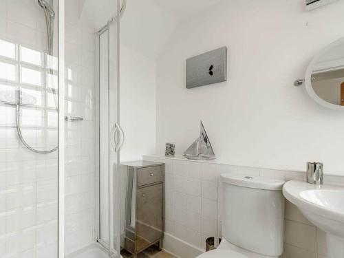 a white bathroom with a toilet and a shower at Cotswolds Lakehouse, with hot tub & spa access, Lower Mill Estate in Somerford Keynes