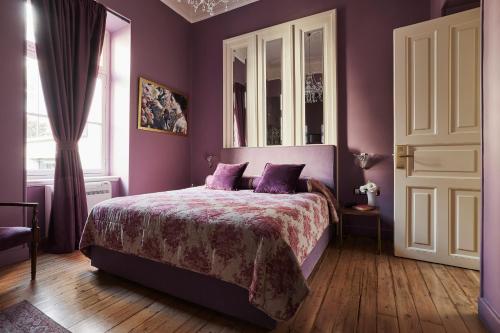 a bedroom with purple walls and a bed with purple pillows at Bohemian Suites Athens in Athens