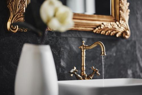 a bathroom sink with a gold faucet and a vase at Bohemian Suites Athens in Athens