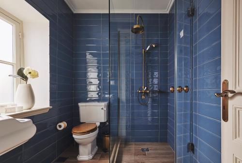 a blue tiled bathroom with a toilet and a shower at Bohemian Suites Athens in Athens