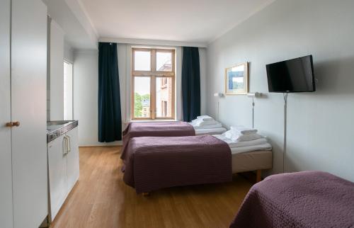 a hotel room with three beds and a flat screen tv at Cochs Pensjonat in Oslo