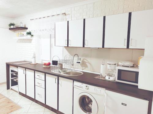 uma cozinha com armários brancos e uma máquina de lavar e secar roupa em Apartment Kesovija em Dubrovnik