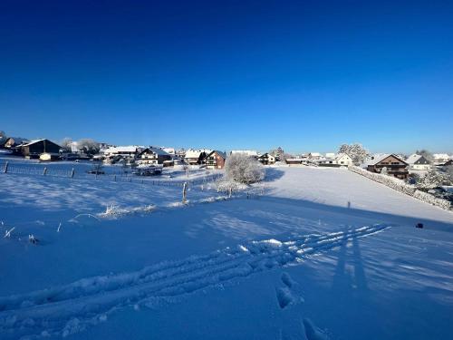 a field covered in snow with houses in the background at Ferienwohnung Katharina 4 Sterne laut DTV Wallbox 11KW in Nideggen
