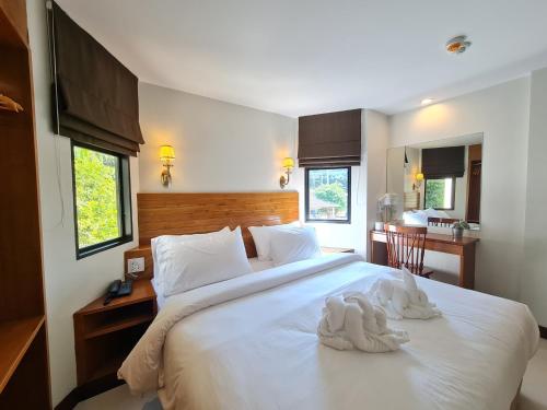 a bedroom with a large white bed with towels on it at The Peace River Kwai in Ban Tha Makham