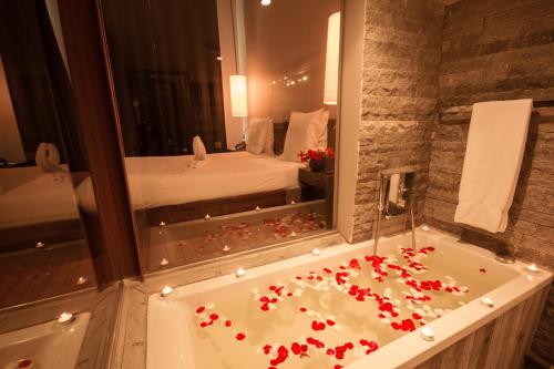 La salle de bains est pourvue d'une baignoire avec des fleurs rouges. dans l'établissement Le Louvre Hotel & Spa, à Antananarivo