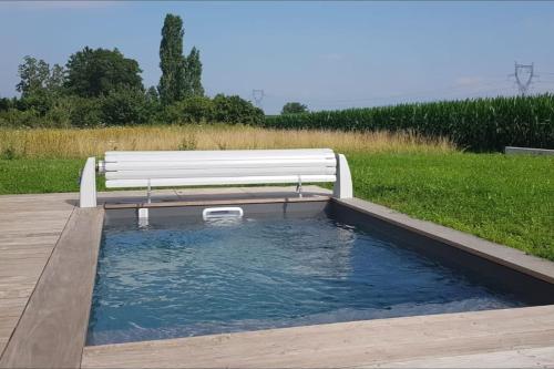 a bench sitting next to a pool of water at Maison Passive avec piscine proche Colmar in Logelheim