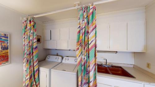 a kitchen with white cabinets and a colorful curtain at ALMOST HEAVEN home in Jekyll Island