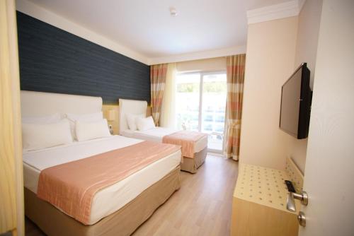 a hotel room with two beds and a flat screen tv at Turunc Resort Hotel in Turunc