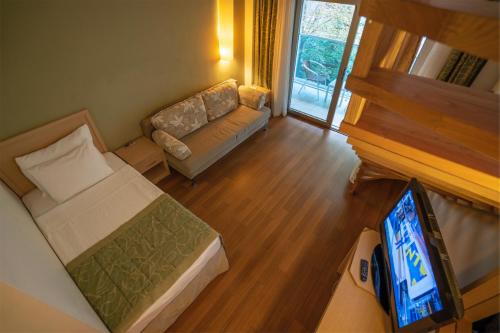 a room with a bed and a couch and a tv at Turunc Resort Hotel in Turunc