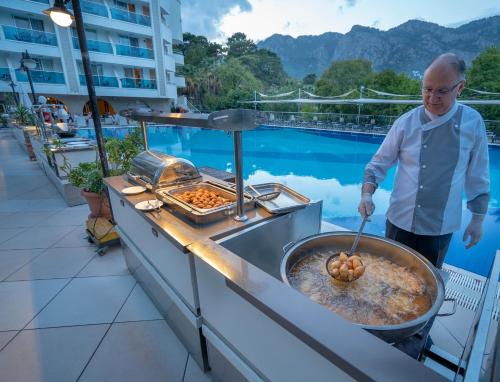 a man cooking food in a grill on a balcony at Turunc Resort Hotel in Turunc