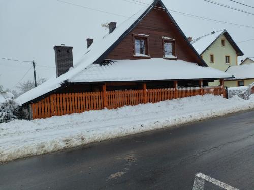 a house covered in snow with a fence at ChatkaDuraje in Jaworzynka
